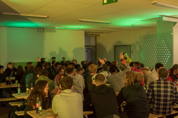Gruppe von Studierenden sitzt an Tischen im Foyer