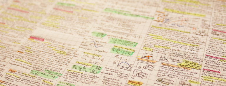 Header Formelsammlung Auf dem Bild ist eine handschriftliche Formelsammlung unscharf zu erkennen.