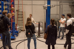 Mitarbeiter erklärt Gruppe von Studierenden Elemente in einer Experimentierhalle