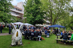 Studierende sitzen an mehreren Biertischen im Freien