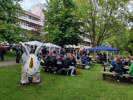 Studierende sitzen an mehreren Biertischen im Freien