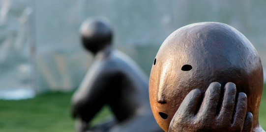 Massive Steinfiguren in nachdenklicher Pose. 