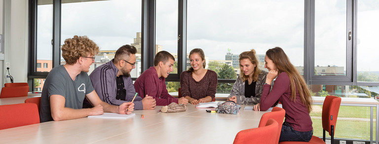Studierende sitzen mit Lernunterlagen am Tisch.