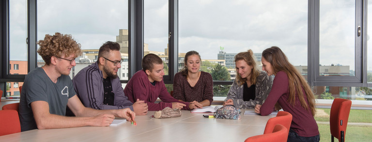 Lerngruppe Studierende sitzen mit Lernunterlagen am Tisch.